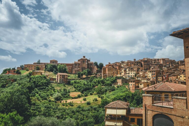 Explore the stunning architecture and lush greenery of San Gimignano, Tuscany under a bright sky.
